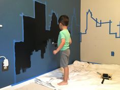 a young boy painting a wall with blue paint