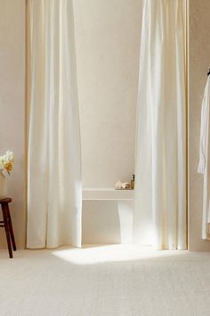 a white bath tub sitting next to a window covered in curtained drapes