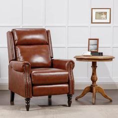 a brown leather recliner chair next to a small table with a clock on it