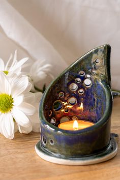 a candle that is sitting on a table next to some flowers and a white flower