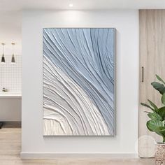 an abstract painting hangs on the wall next to a potted plant in a bathroom