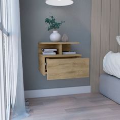 a small wooden shelf with books and vases on it next to a bed in a bedroom