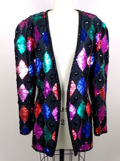 "This stunning vintage piece heavily embellished with black beading, colorful sequins and accented with black rhinestones in a retro harlequin design. It's in excellent condition! Some of the photos are lightened to show the amazing details. Measurements are taken with the front closure intact. MEASUREMENTS: Bust - 36/38\" Waist - 28\" Shoulders - 16\" Sleeves - 24\" Top to Bottom Length - 29\" Tag Size - 8 All of my items come from a smoke-free and pet-free home. If you have any questions, plea Fitted Multicolor Sequined Outerwear, Embellished Multicolor Party Outerwear, Multicolor Embellished Party Outerwear, Festive Multicolor Embellished Outerwear, Fitted Multicolor Evening Outerwear, Evening Coat, Checkered Jacket, Sequin Blazer, Fitted Jacket