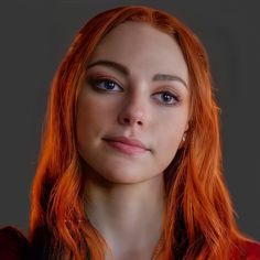 a woman with red hair and blue eyes looks at the camera while wearing a necklace