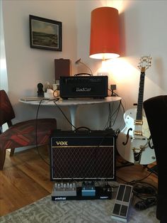 two amps are sitting on the floor in front of a table with a guitar