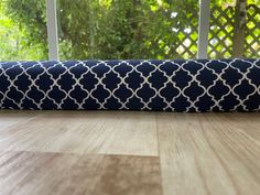 a blue and white pillow sitting on top of a wooden floor next to a window