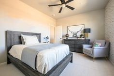 a bedroom with a large bed, chair and ceiling fan in it's corner