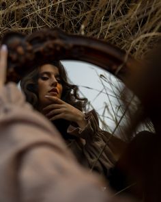 a woman is looking at herself in the mirror with her hand on her chin and holding up one finger