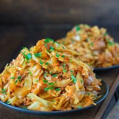 two black bowls filled with coleslaw on top of a wooden table next to each other