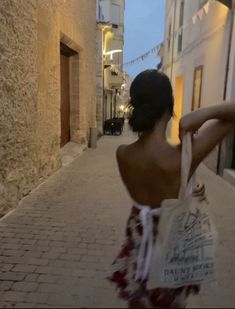 a woman walking down a street carrying a bag