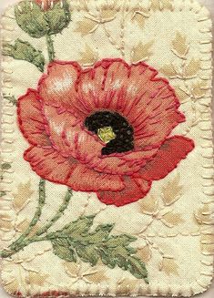 a close up of a red flower on a piece of cloth with green leaves and flowers