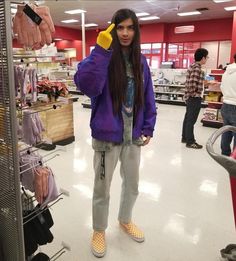 a woman standing in a store talking on a cell phone while wearing slippers and a purple jacket