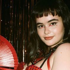 a woman with dark hair holding a red fan