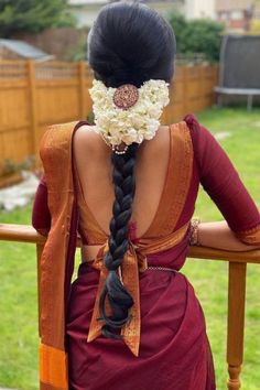 the back of a woman's head with flowers in her hair, sitting on a wooden bench