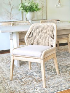 two wicker chairs sitting on top of a rug in front of a white table