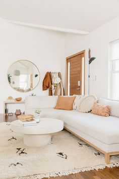 a living room with a white couch and round coffee table in front of a mirror