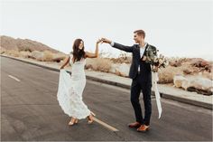 a bride and groom walking down the road holding hands