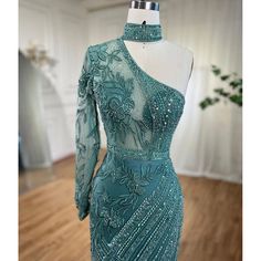 Striking turquoise color exudes vibrancy and elegance. One-shoulder design adds a touch of sophistication. Mermaid silhouette accentuates curves for a flattering fit. Adorned with intricate beadwork for a glamorous look. Perfect for women's wedding parties and formal events. Crafted with high-quality materials for comfort and durability. Embodies grace and style for a memorable occasion. Glamorous Look, Mermaid Silhouette, Wedding Parties, Mermaid Evening Dresses, Shoulder Design, Turquoise Color, Formal Event, Evening Dress, Bead Work