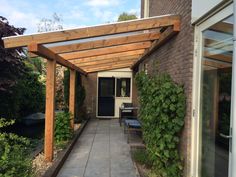 an outdoor patio area with wooden pergoline and stone walkway leading to the front door