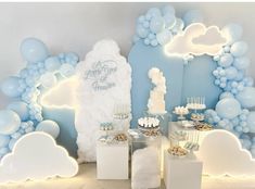 the dessert table is set up with blue and white balloons, clouds, and cake