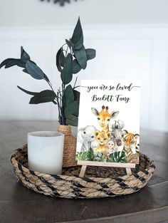 a basket with a card, candle and some plants on it that says you are so loved by the little giraffes