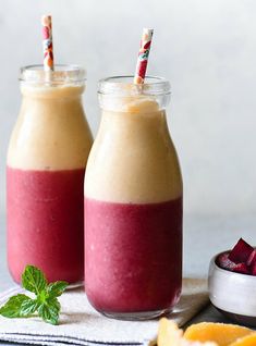 two glasses filled with smoothie next to sliced oranges