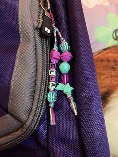 a close up of a purple backpack with beads and charms on the front zippers