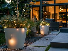 two large white planters with lights in them on the side of a house at night