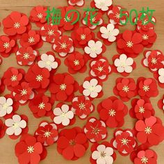 red and white paper flowers are arranged on a wooden surface with the words, happy new year written in japanese