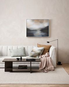 a living room with a couch, coffee table and painting on the wall above it