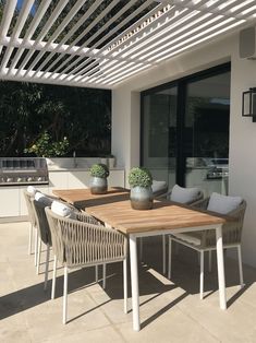 a wooden table sitting on top of a patio under a pergolated roof with potted plants