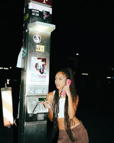 a woman standing next to a parking meter talking on a cell phone while holding onto her ear