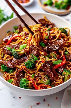 a white bowl filled with beef and broccoli stir - fry on top of a table