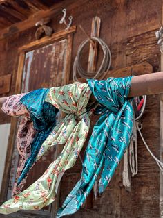 several scarves are hanging on a clothes line in front of an old wooden building