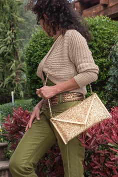 a woman in green pants holding a gold purse