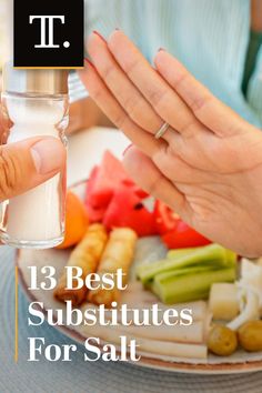 a person holding a salt shaker over a plate of food