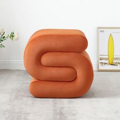 an orange chair sitting on top of a carpeted floor next to a vase with flowers