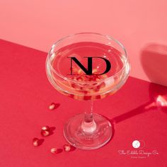 a glass filled with liquid and nuts on top of a red tablecloth next to a pink wall