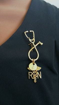 a woman wearing a black shirt with a gold medical charm on it