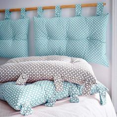 a bed with blue and white pillows on it's headboard next to a window