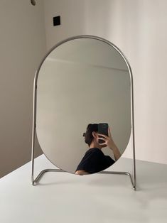 a woman taking a selfie in front of a large mirror with her cell phone