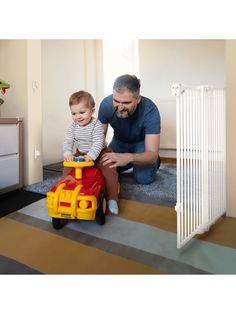 a man playing with a toddler on the floor in front of a toy train