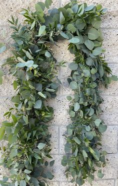 a wreath made out of green leaves on a brick wall with the word love written in it