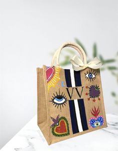 a handbag with an eye design on it sitting on a marble table next to a plant