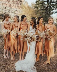 a group of women standing next to each other in front of some tall trees and grass