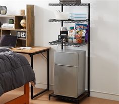 a room with a bed, refrigerator and shelves on the wall next to a desk