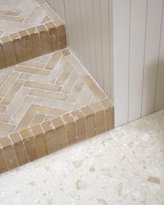 a white and tan tiled stair case next to a wall