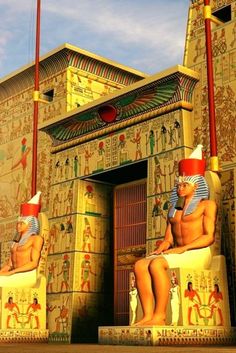 two egyptian statues sitting on the outside of a building