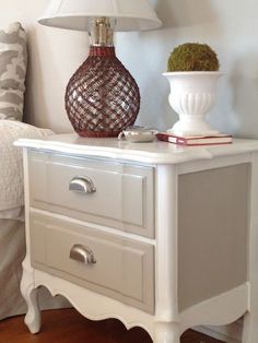 a white nightstand with two drawers and a lamp