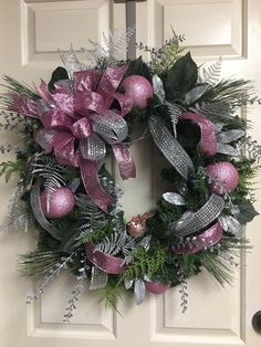 a pink and silver christmas wreath on a door